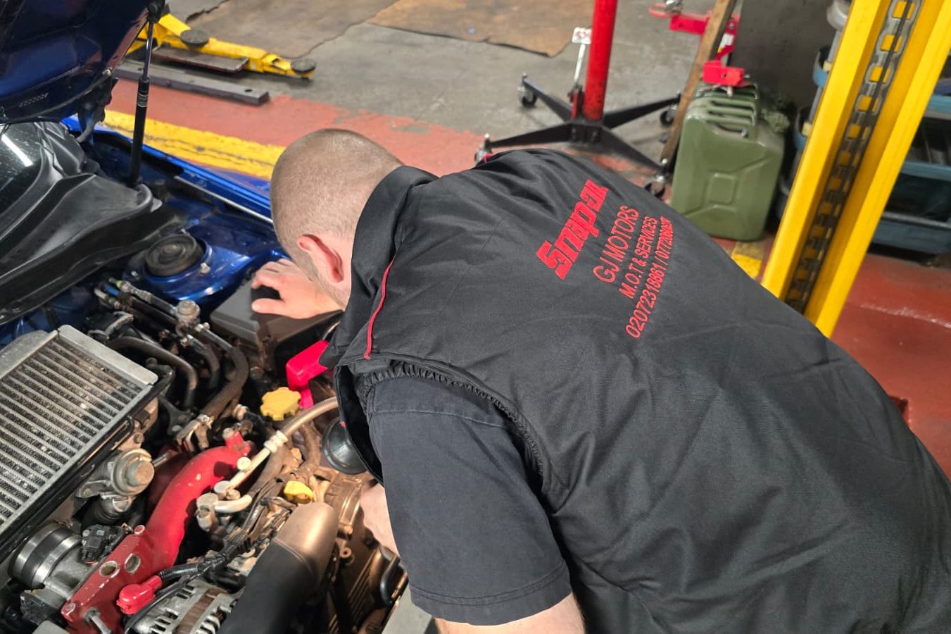 Vehicle Servicing Mechanic working on a car engine, focused on repairs in a workshop.