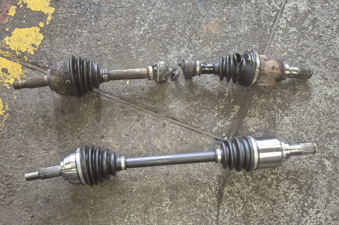 Vehicle Suspension Specialist Two car axle shafts positioned side by side on the workshop floor.